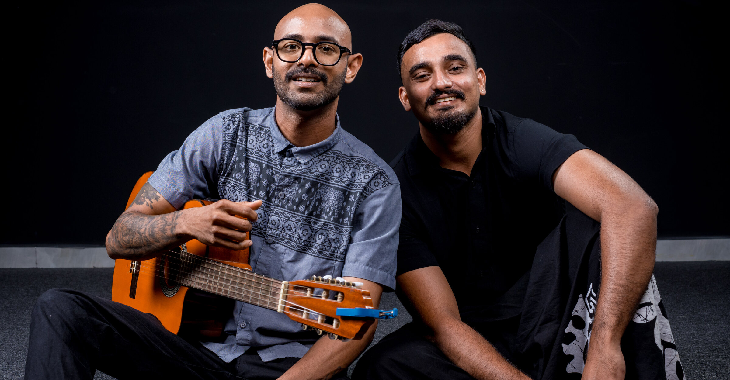 Hasith and Stefan of Authentic, seated together with a classical guitar